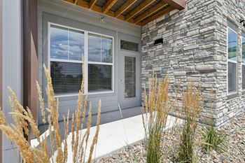 The front porch of a home with stone walls and a wood ceiling